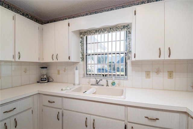 kitchen with a textured ceiling, light countertops, tasteful backsplash, and a sink