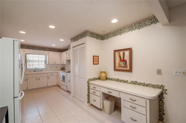 kitchen featuring light tile patterned floors, light countertops, built in study area, a textured ceiling, and white appliances