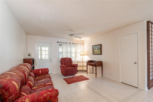 living room with light tile patterned flooring, ceiling fan, a textured ceiling, and baseboards