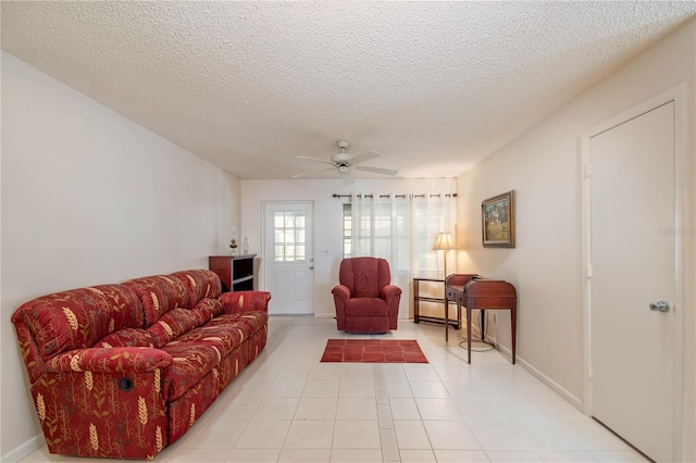 living area with ceiling fan, light tile patterned floors, a textured ceiling, and baseboards