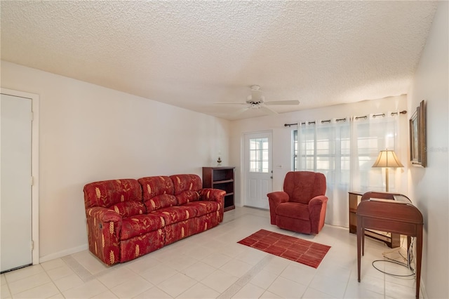 living room with ceiling fan, a textured ceiling, and baseboards