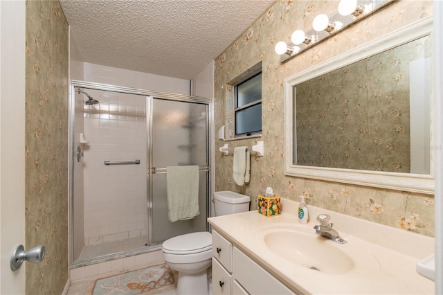 bathroom featuring a textured ceiling, toilet, vanity, a stall shower, and wallpapered walls