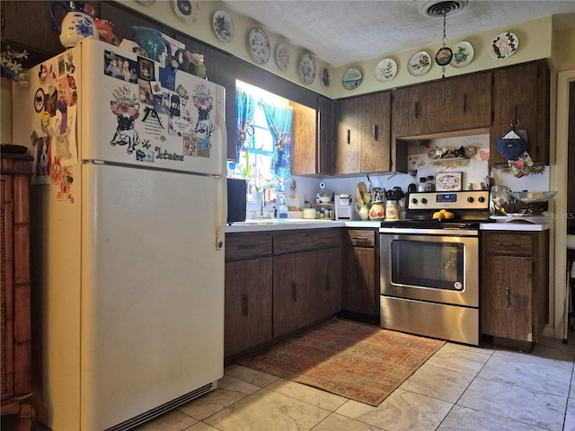 kitchen featuring a textured ceiling, stainless steel range with electric cooktop, dark brown cabinetry, and white fridge