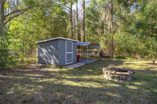 view of yard with an outdoor fire pit, a storage shed, and a carport