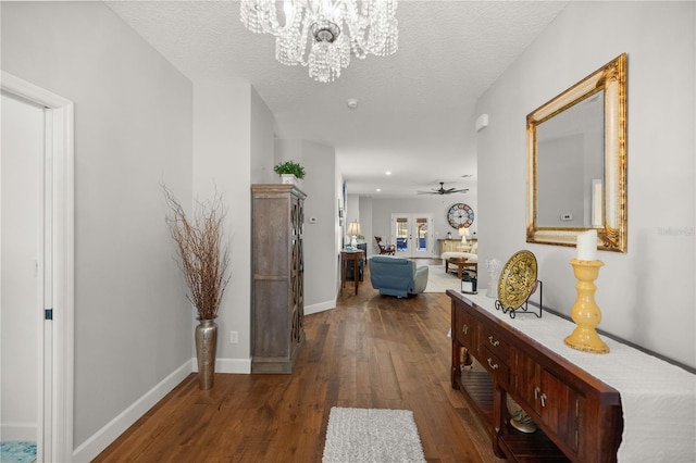 corridor featuring a notable chandelier, dark wood-type flooring, and a textured ceiling