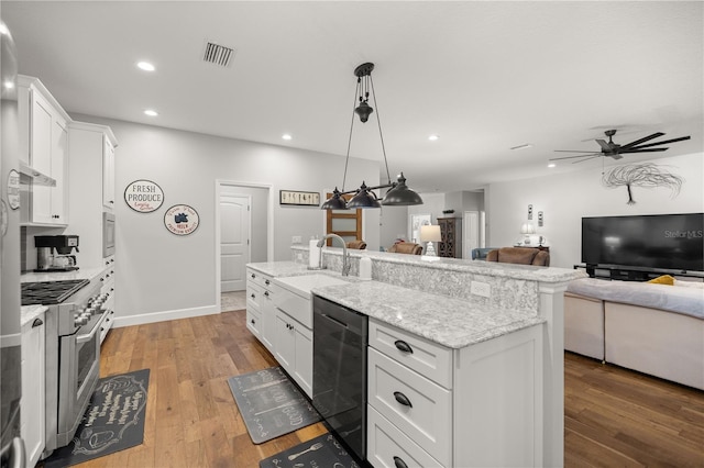 kitchen featuring pendant lighting, stainless steel stove, white cabinets, and a kitchen island with sink