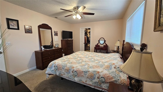 bedroom featuring a spacious closet, ceiling fan, light carpet, a textured ceiling, and a closet