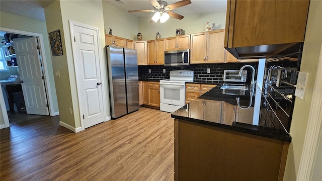 kitchen featuring sink, light hardwood / wood-style flooring, kitchen peninsula, stainless steel appliances, and backsplash