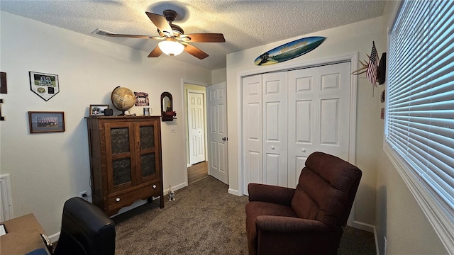 living area featuring dark colored carpet, a textured ceiling, and ceiling fan