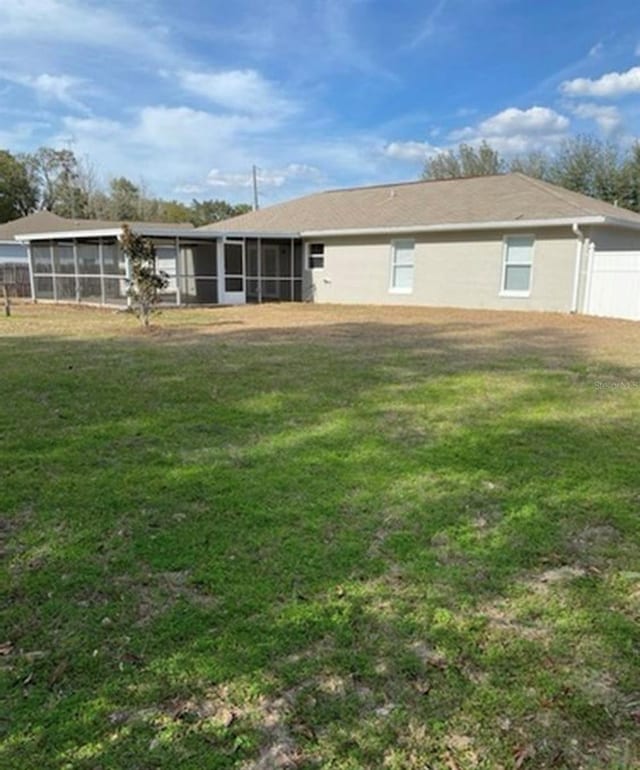 rear view of house with a lawn and a sunroom