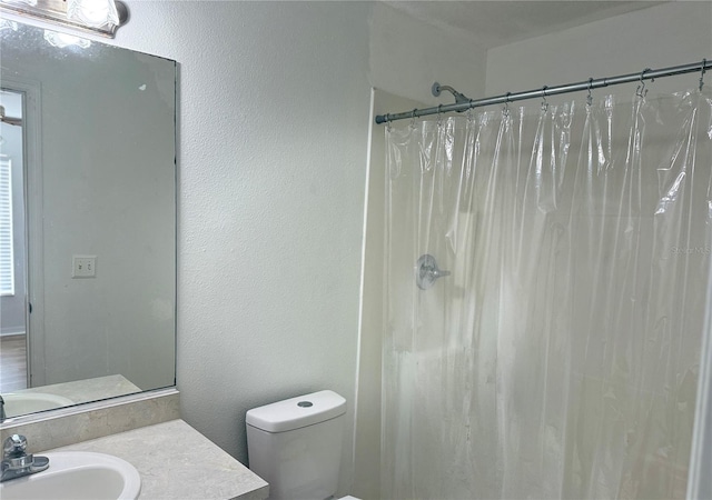 bathroom with walk in shower, vanity, and toilet