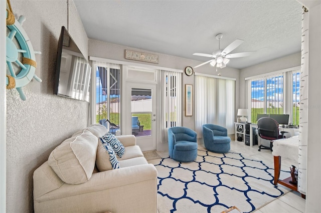 living room featuring ceiling fan and a textured ceiling