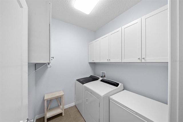 clothes washing area featuring a textured ceiling, light tile patterned floors, cabinets, and independent washer and dryer