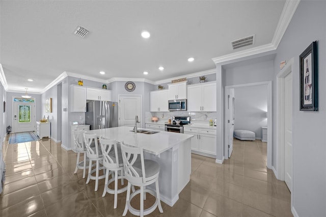 kitchen with a kitchen bar, a kitchen island with sink, white cabinets, sink, and stainless steel appliances