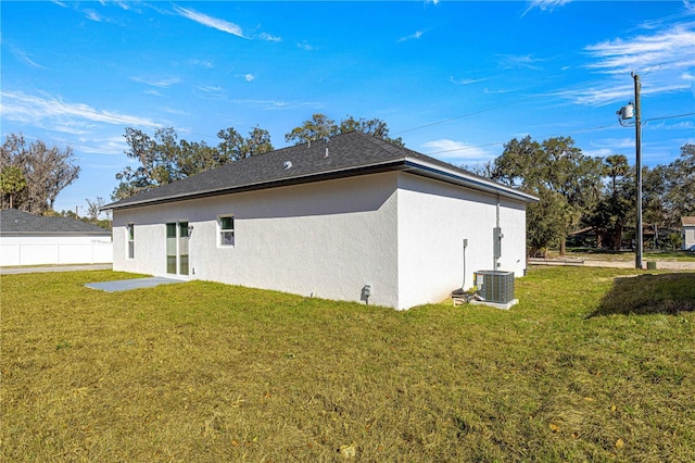 rear view of house featuring central AC unit and a lawn