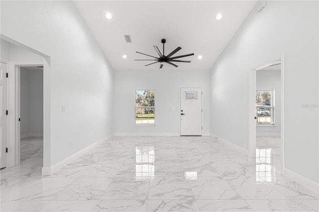 interior space with a healthy amount of sunlight, a towering ceiling, and ceiling fan