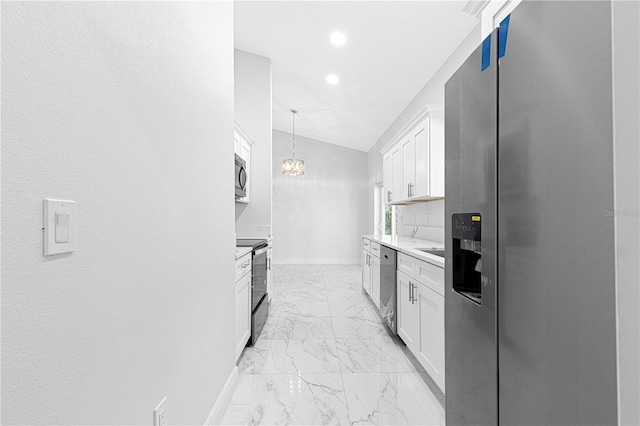 kitchen featuring lofted ceiling, appliances with stainless steel finishes, decorative light fixtures, and white cabinets