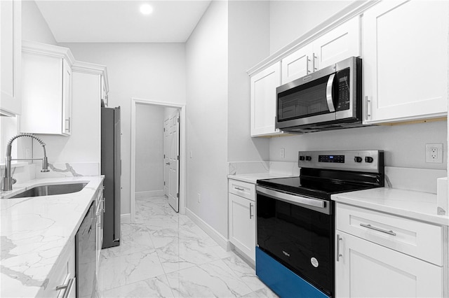 kitchen featuring light stone counters, stainless steel appliances, sink, and white cabinets