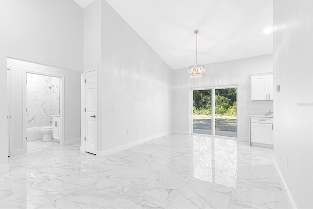 spare room featuring an inviting chandelier and high vaulted ceiling