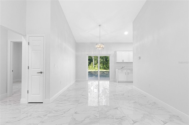 unfurnished room with an inviting chandelier and a high ceiling