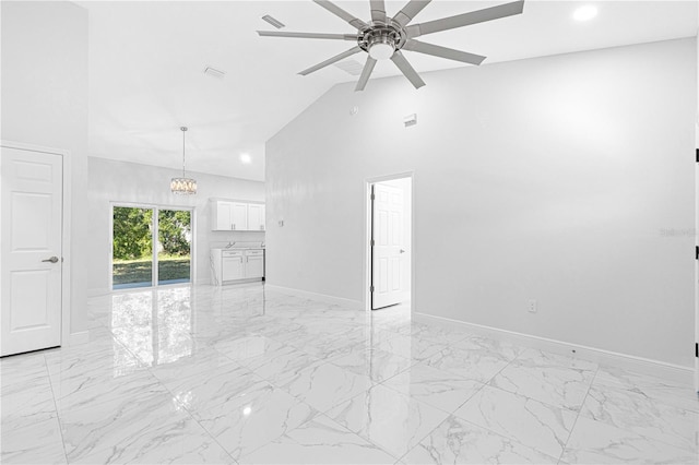 unfurnished living room featuring ceiling fan with notable chandelier and high vaulted ceiling