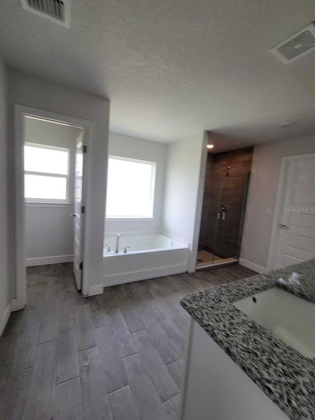 bathroom with wood-type flooring, vanity, and shower with separate bathtub