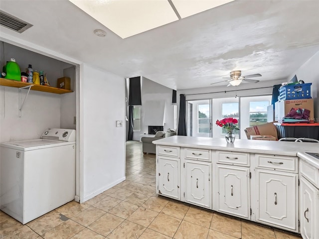 kitchen with kitchen peninsula, ceiling fan, washer / dryer, white cabinets, and light tile patterned flooring