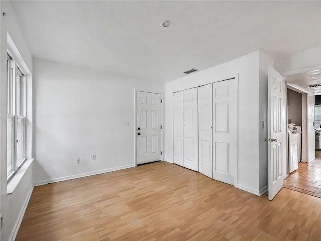 unfurnished bedroom with light hardwood / wood-style flooring and washer / dryer