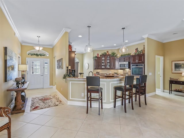 kitchen featuring light tile patterned flooring, dark brown cabinetry, appliances with stainless steel finishes, and a breakfast bar area