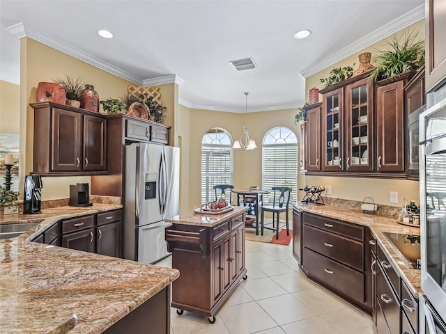 kitchen featuring stainless steel refrigerator with ice dispenser, dark brown cabinets, ornamental molding, pendant lighting, and light stone countertops