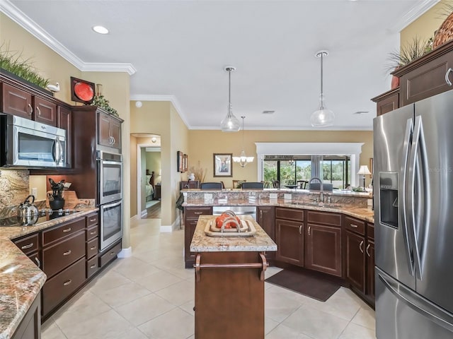 kitchen featuring sink, appliances with stainless steel finishes, hanging light fixtures, ornamental molding, and a kitchen island