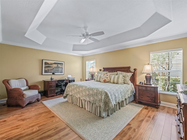 bedroom with ornamental molding, ceiling fan, light hardwood / wood-style floors, and a tray ceiling