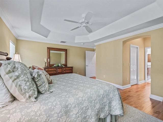 bedroom with a tray ceiling, wood-type flooring, ornamental molding, and ceiling fan