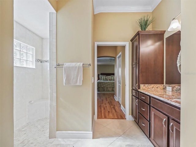 bathroom featuring tile patterned floors, ornamental molding, tiled shower, and vanity