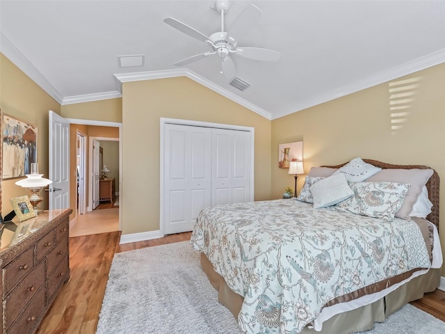 bedroom featuring ornamental molding, lofted ceiling, a closet, and light wood-type flooring