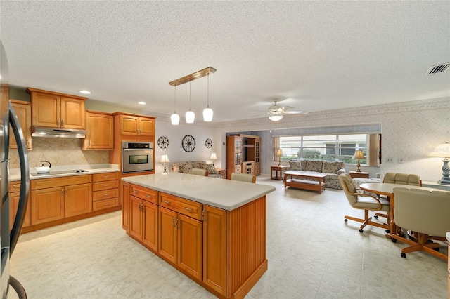 kitchen with stainless steel oven, a center island, decorative backsplash, pendant lighting, and ceiling fan