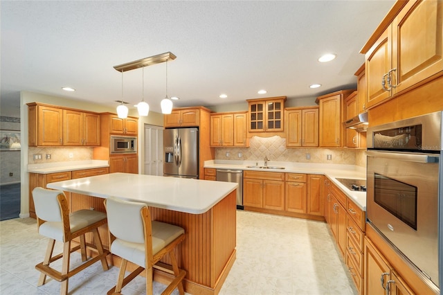 kitchen featuring appliances with stainless steel finishes, a kitchen island, decorative light fixtures, a kitchen breakfast bar, and backsplash