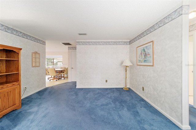 spare room featuring dark colored carpet and a textured ceiling