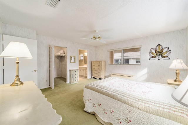 bedroom featuring a walk in closet, ensuite bath, light carpet, a closet, and ceiling fan