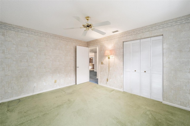 unfurnished bedroom with ceiling fan, a closet, and carpet flooring