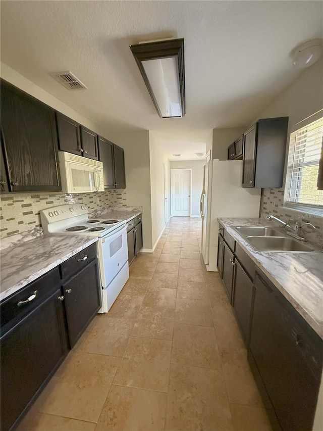 kitchen featuring sink, dark brown cabinetry, white appliances, and tasteful backsplash