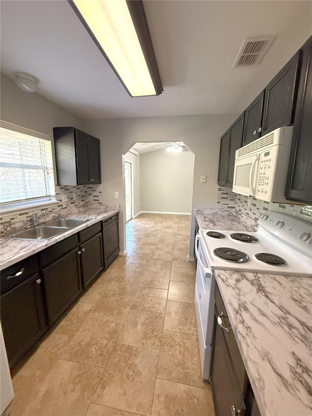 kitchen featuring white appliances, tasteful backsplash, light tile patterned floors, sink, and light stone counters