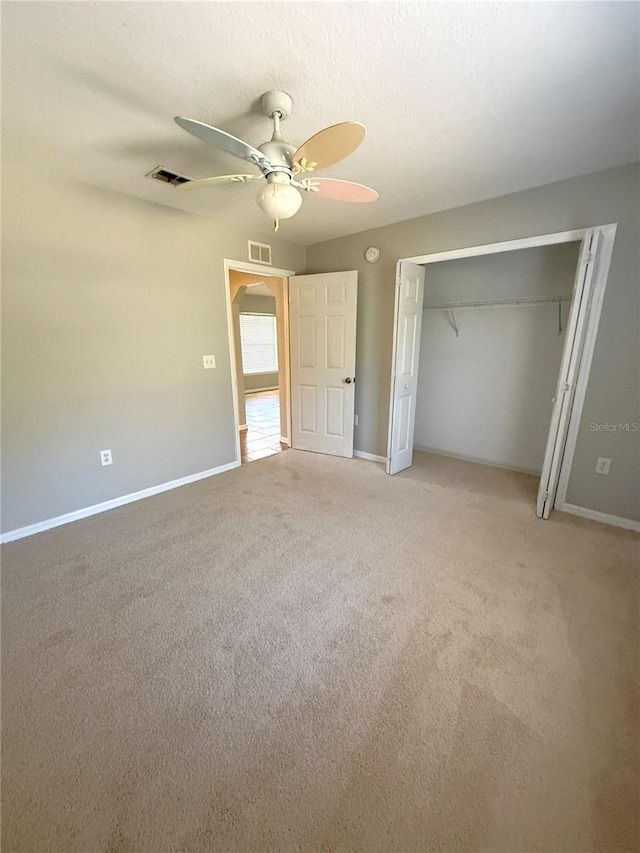 unfurnished bedroom with ceiling fan, a closet, and light carpet