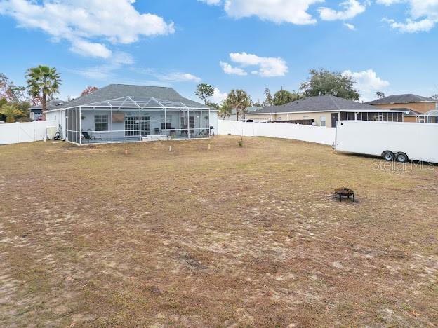 view of yard featuring an outdoor fire pit and a lanai