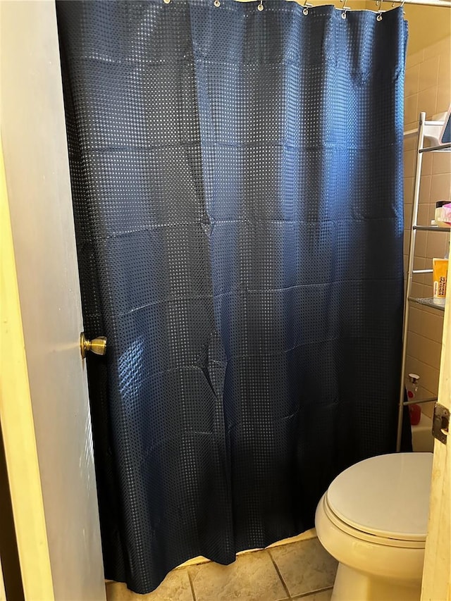 bathroom featuring tile patterned flooring, a shower with shower curtain, and toilet