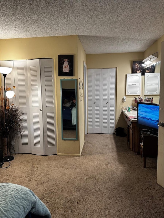 carpeted bedroom featuring multiple closets and a textured ceiling