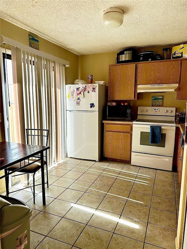 kitchen with white appliances, a textured ceiling, and light tile patterned floors