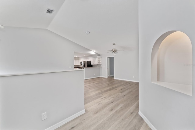 unfurnished living room featuring ceiling fan, light wood-type flooring, and vaulted ceiling