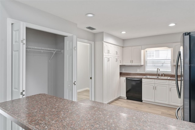 kitchen with white cabinets, dishwasher, sink, stainless steel fridge, and light wood-type flooring