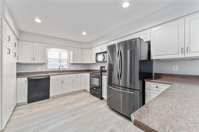 kitchen with black appliances, light wood-type flooring, white cabinets, and sink